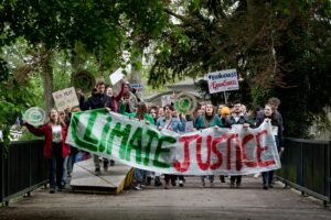 Group of activists marching for climate justice in Maastricht with banners and signs.