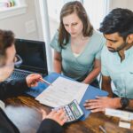 Young couple meeting with real estate agent to discuss property purchase.